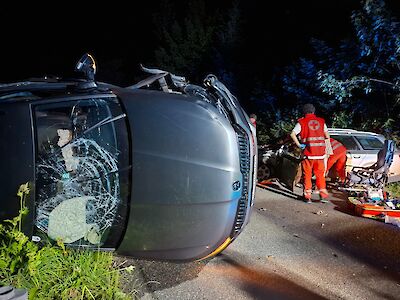 Unfall mit umgekipptem Auto und Rettungskräften des Roten Kreuzes auf der Straße